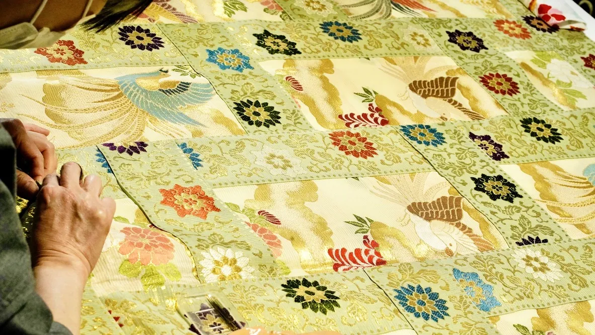 Hands sewing pale green brocade