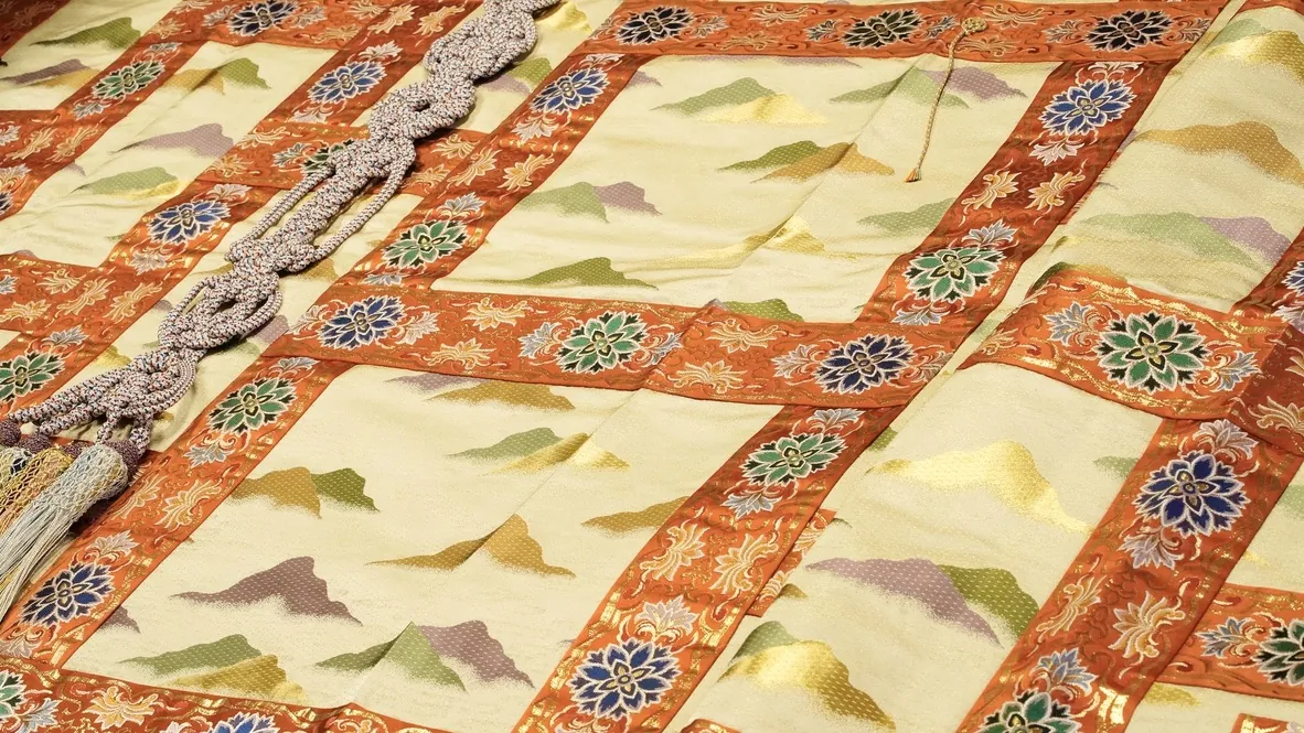 Gold-and-orange brocade with a pattern of mountains laid out with a grey-silver cord